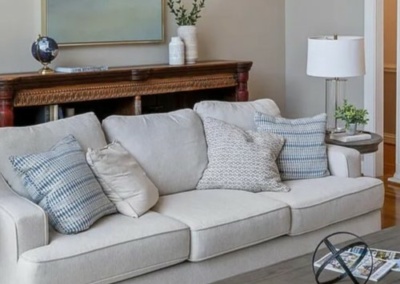white sofa, transitional style furnishings, round drum lamp shade, antique bookcase