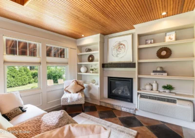 Pinewood ceiling, built-in bookcases surrounding fireplace, painted concrete floor, sunporch